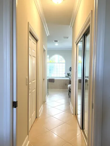 a view of a hallway with wooden floor a glass door and a bathroom