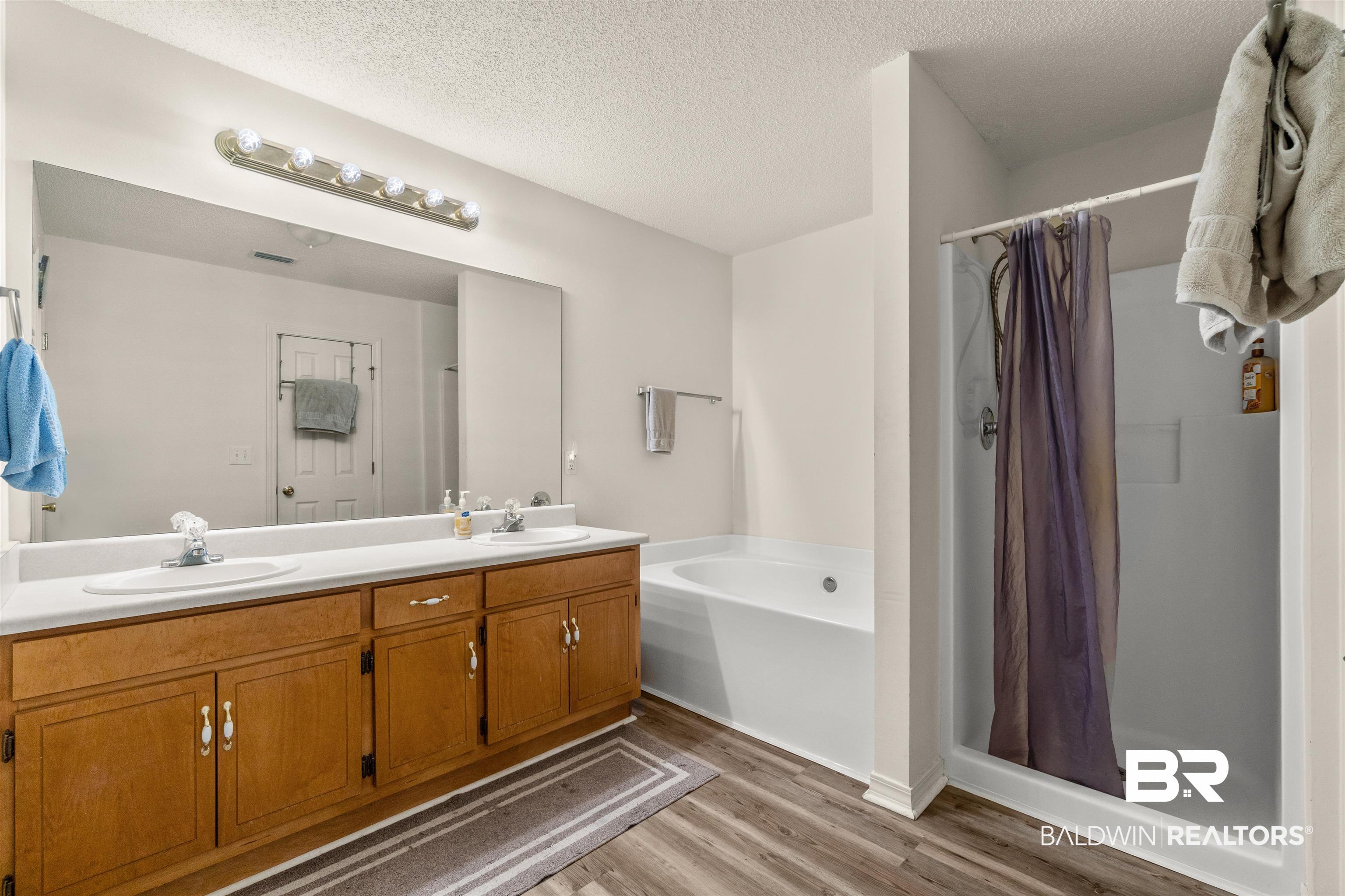 35893 Pine Road South Stapleton, AL 36578 - Photo 17 of 31 Bathroom featuring a wood-finish vanity with dual sinks, a large wall-mounted mirror, and an overhead vanity light fixture
