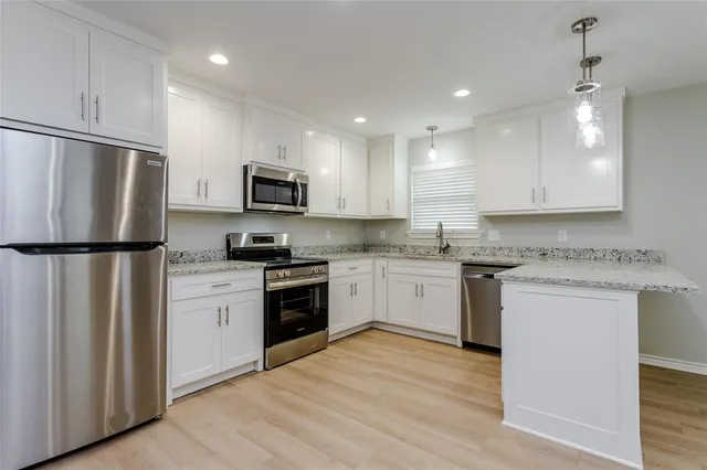 a kitchen with granite countertop a refrigerator stove top oven and sink