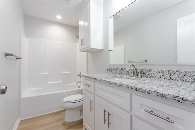 a bathroom with a granite countertop sink a toilet and bathtub