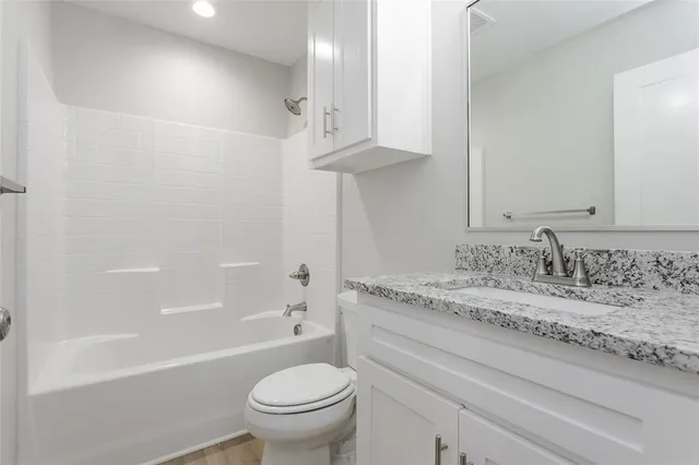 a bathroom with a granite countertop sink a toilet and bathtub