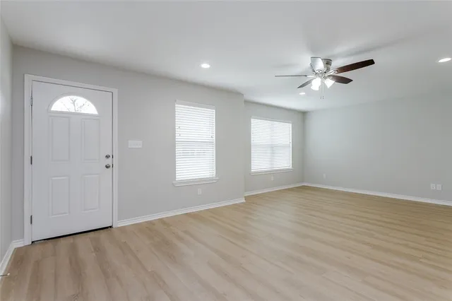 an empty room with wooden floor ceiling fan with window