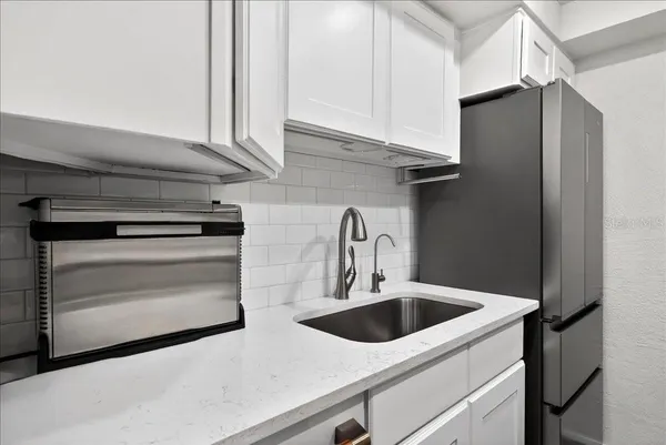 a utility room with stainless steel appliances a refrigerator and a sink