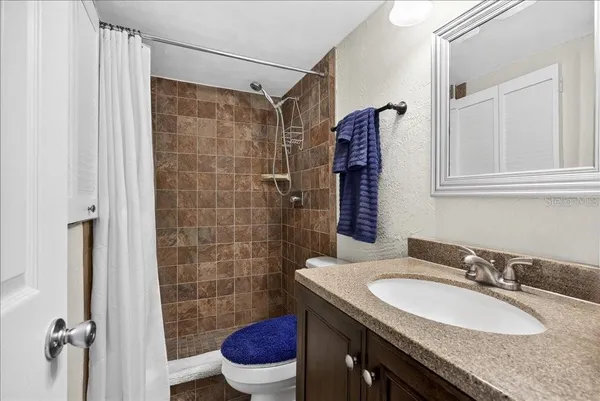 a bathroom with a granite countertop sink toilet and shower