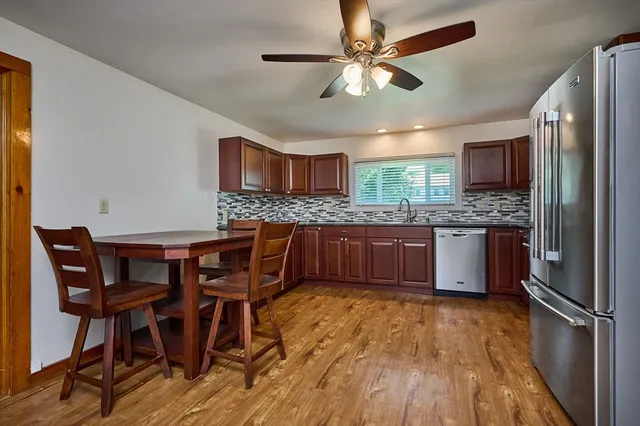 a kitchen with stainless steel appliances granite countertop wooden floor a dining table and chairs