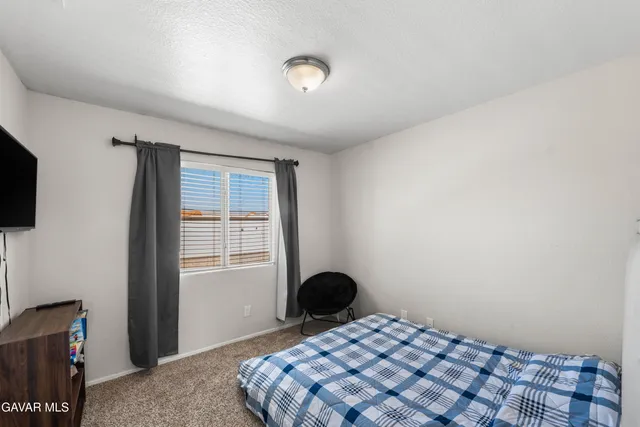 a bedroom with a bed and a flat tv screen on the dresser