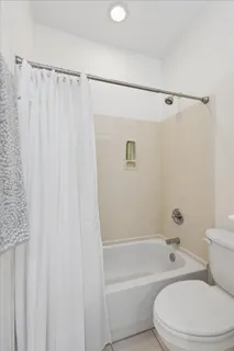 a white toilet sitting next to a bath tub