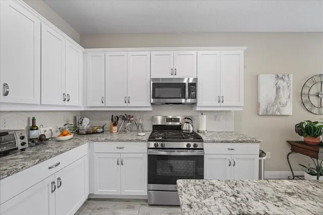 a kitchen with granite countertop white cabinets and stainless steel appliances