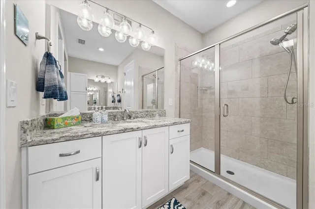 a bathroom with a granite countertop sink mirror and shower