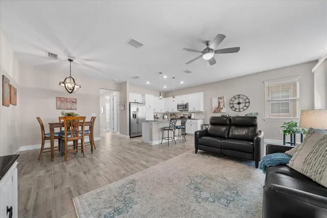 a living room with furniture kitchen view and a wooden floor