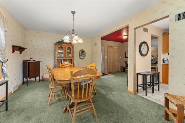 a view of a dining room and kitchen with furniture wall clock and a chandelier