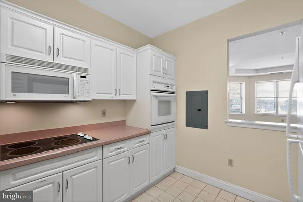 a kitchen with stainless steel appliances granite countertop white cabinets and window