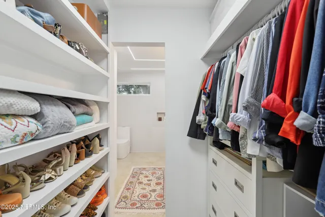 a view of walk in closet with clothes and shoes