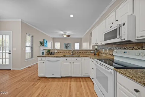 a white kitchen with stainless steel appliances granite countertop a stove and white cabinets