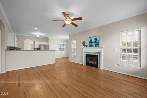 an empty room with wooden floor chandelier fan and windows
