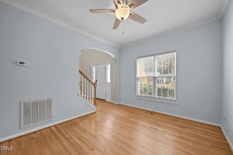 a view of an empty room with wooden floor and a window