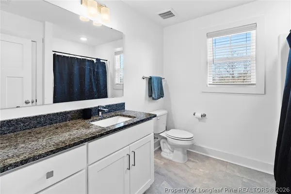 a bathroom with a granite countertop toilet sink and mirror