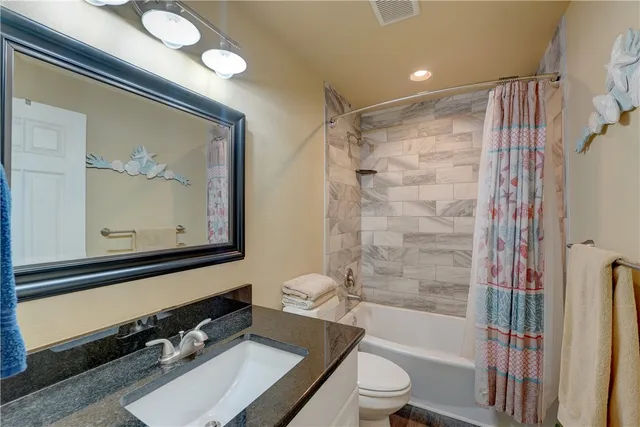 a bathroom with a bathtub shower sink vanity and toilet