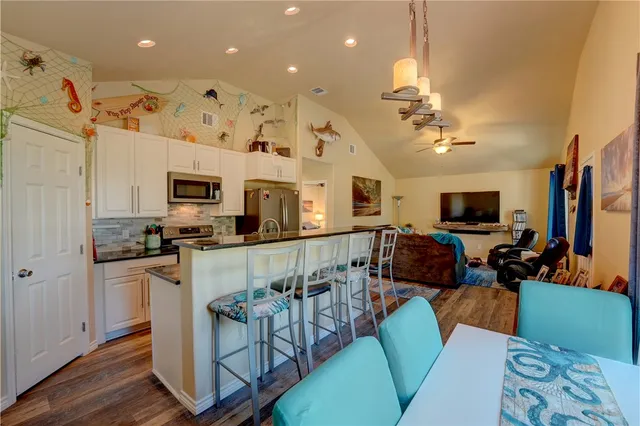 a living room with stainless steel appliances furniture and a flat screen tv