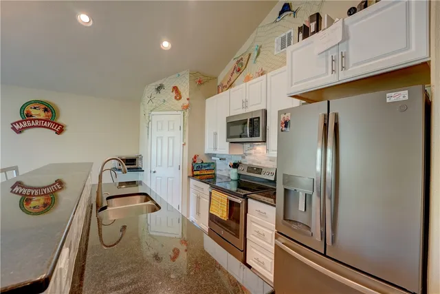 a kitchen with stainless steel appliances granite countertop a refrigerator a stove and a sink