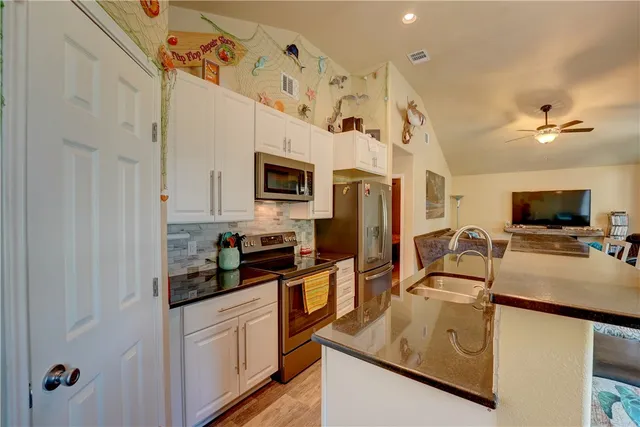 a kitchen with stainless steel appliances granite countertop a sink a stove cabinets and a refrigerator