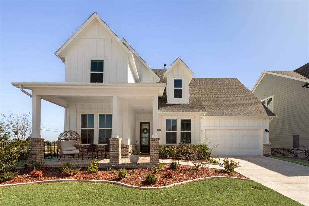 View of front of home featuring a garage, roof with shingles, board and batten siding, and covered porch