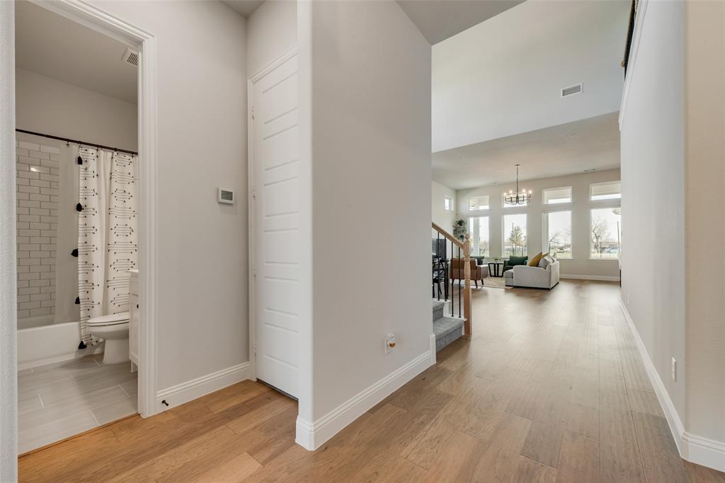 8922 Edna Place Rowlett, TX 75089 - Photo 7 of 37 Corridor with stairway, a notable chandelier, light wood-style floors, and baseboards