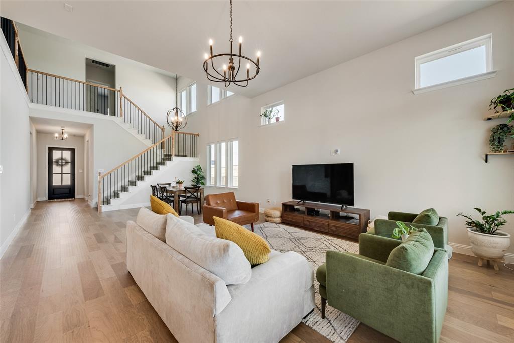 8922 Edna Place Rowlett, TX 75089 - Photo 9 of 37 Living room with baseboards, stairs, light wood-style flooring, a high ceiling, and a notable chandelier
