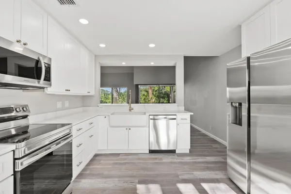 a kitchen with white cabinets and stainless steel appliances