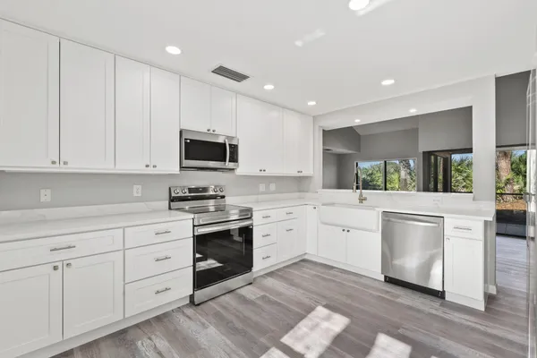 a kitchen with white cabinets and appliances
