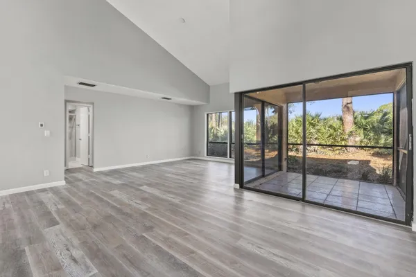 a view of empty room with wooden floor and floor to ceiling window