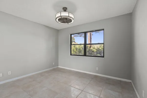 an empty room with windows and fan