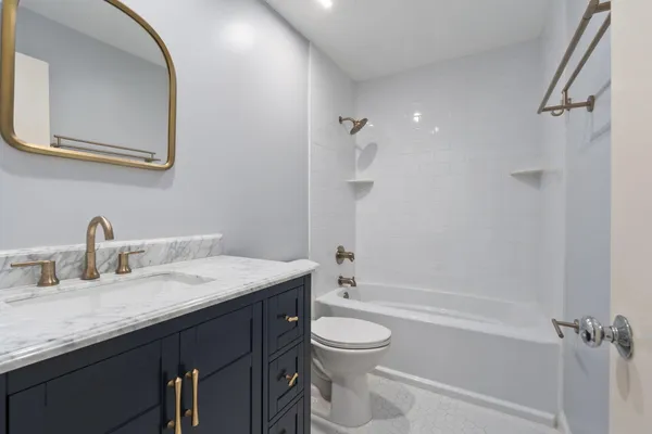 a bathroom with a granite countertop sink a toilet and shower