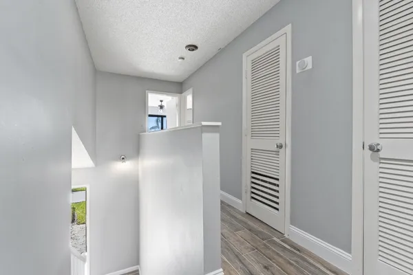 a view of a hallway with wooden floor and a bathroom