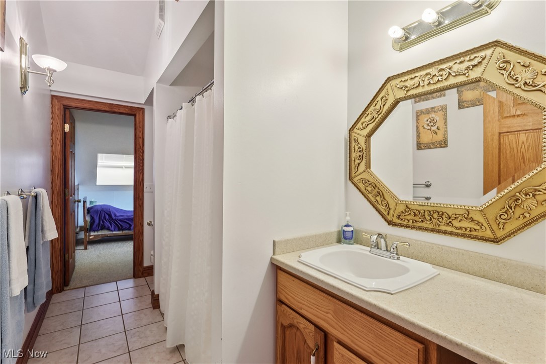 337 Cedar Point Road Sandusky, OH 44870 - Photo 23 of 50 Ensuite bathroom featuring light tile patterned floors, vanity, a shower with shower curtain, and light colored carpet