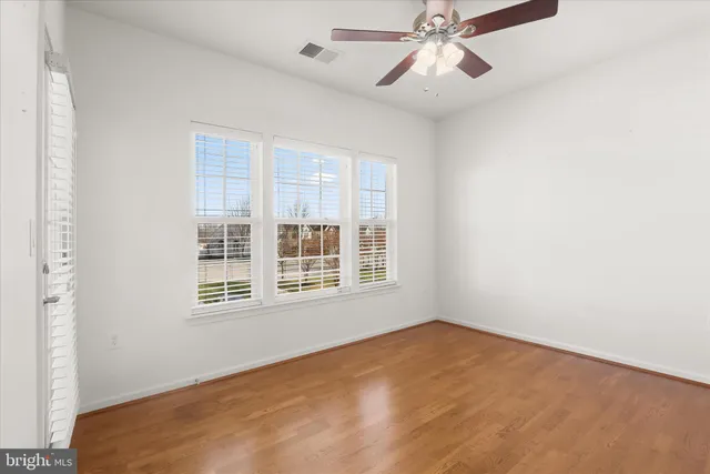an empty room with chandelier fan and windows
