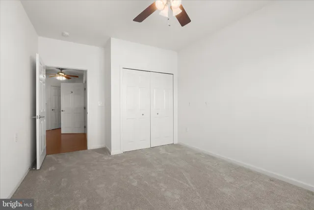 an empty room with closet and chandelier fan
