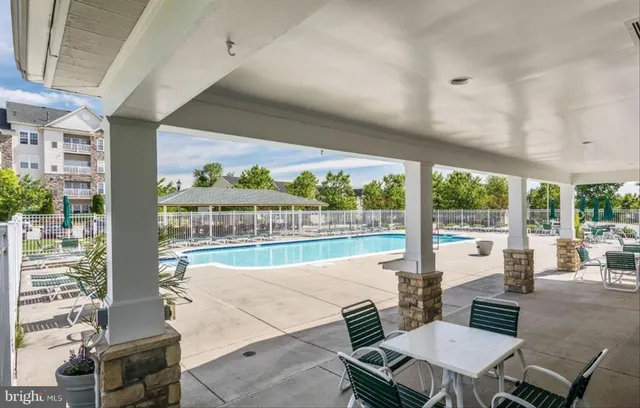 a view of swimming pool with seating area and trees in the background