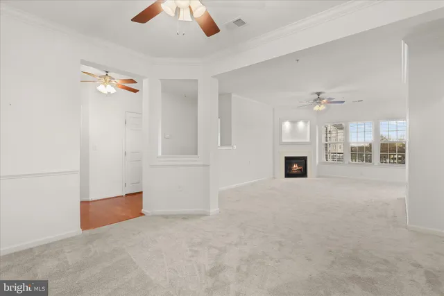 an empty room with chandelier fan and windows
