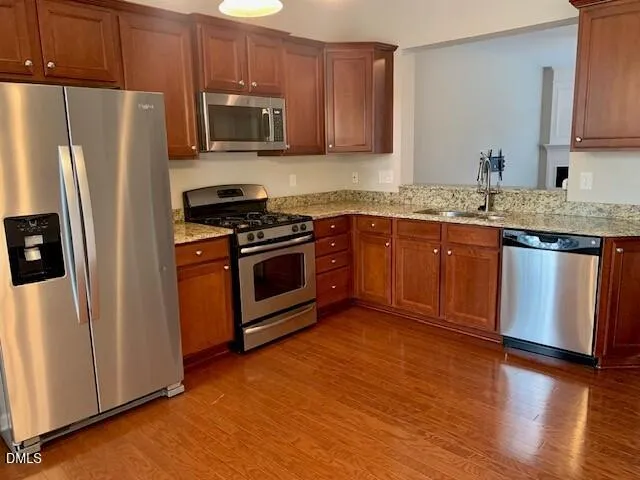 a kitchen with granite countertop wooden cabinets a stove a microwave and a refrigerator