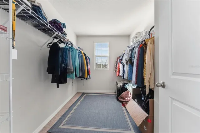 a view of walk in closet with clothes and shoes