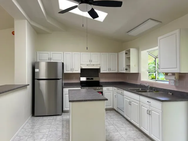 a kitchen with stainless steel appliances granite countertop a refrigerator a stove a sink and white cabinets