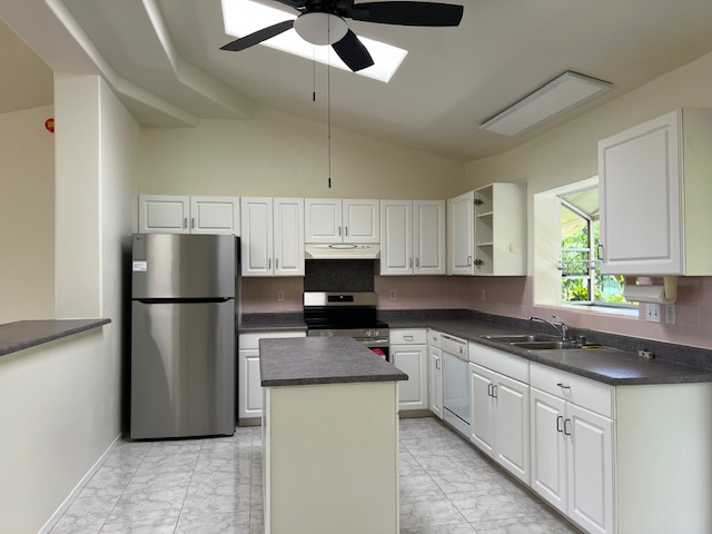 3320 B Wawae Road Kalaheo, HI 96741 - Photo 4 of 15 a kitchen with stainless steel appliances granite countertop a refrigerator a stove a sink and white cabinets
