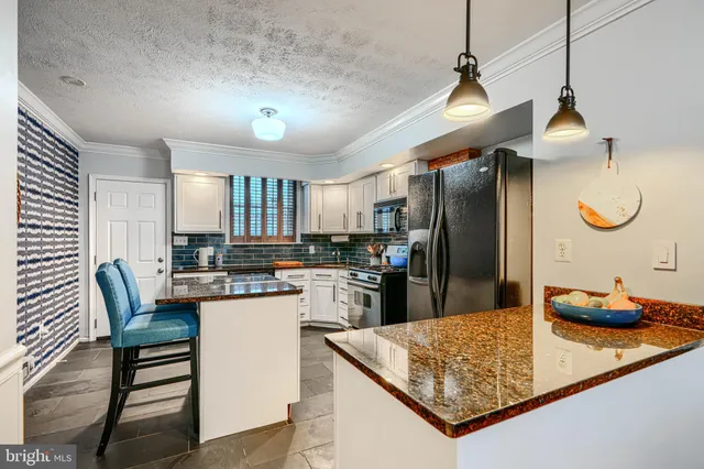 a kitchen with stainless steel appliances granite countertop a refrigerator a stove a sink dishwasher and white cabinets with wooden floor