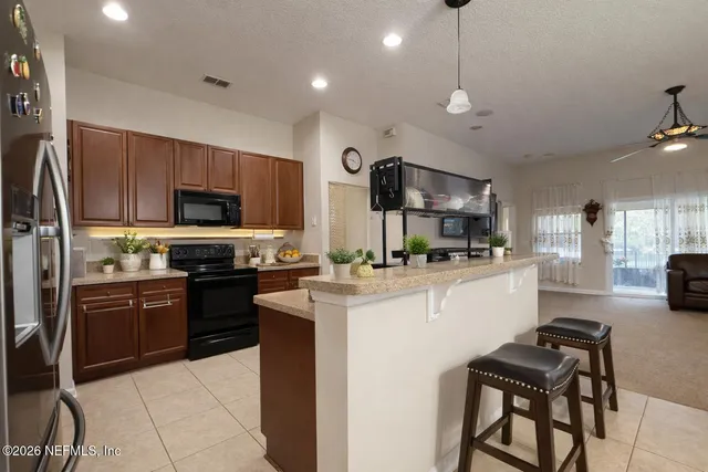 a kitchen with stainless steel appliances kitchen island granite countertop a stove top oven a sink a refrigerator a dining table and chairs