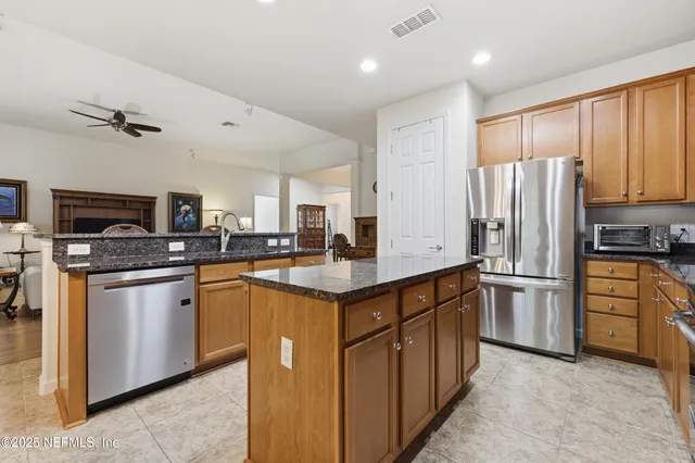 a kitchen with stainless steel appliances granite countertop a refrigerator a stove top oven a sink and dishwasher