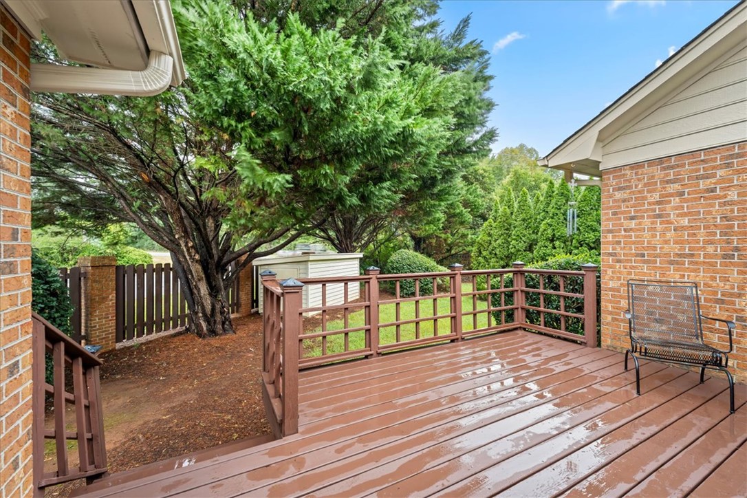 2004 Cardinal Park Drive Anderson, SC 29621 - Photo 36 of 40 Mature trees frame a spacious wooden deck set against a classic brick exterior.