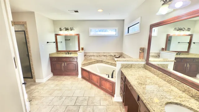 a spacious bathroom with a tub sink and mirror