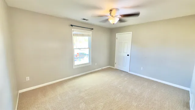 an empty room with a window and a ceiling fan