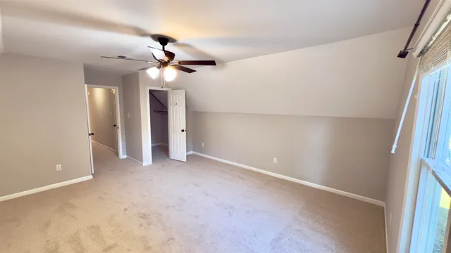 a view of a room with a ceiling fan and carpet
